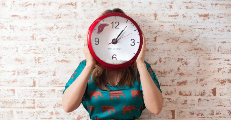 woman covering face using wall clock